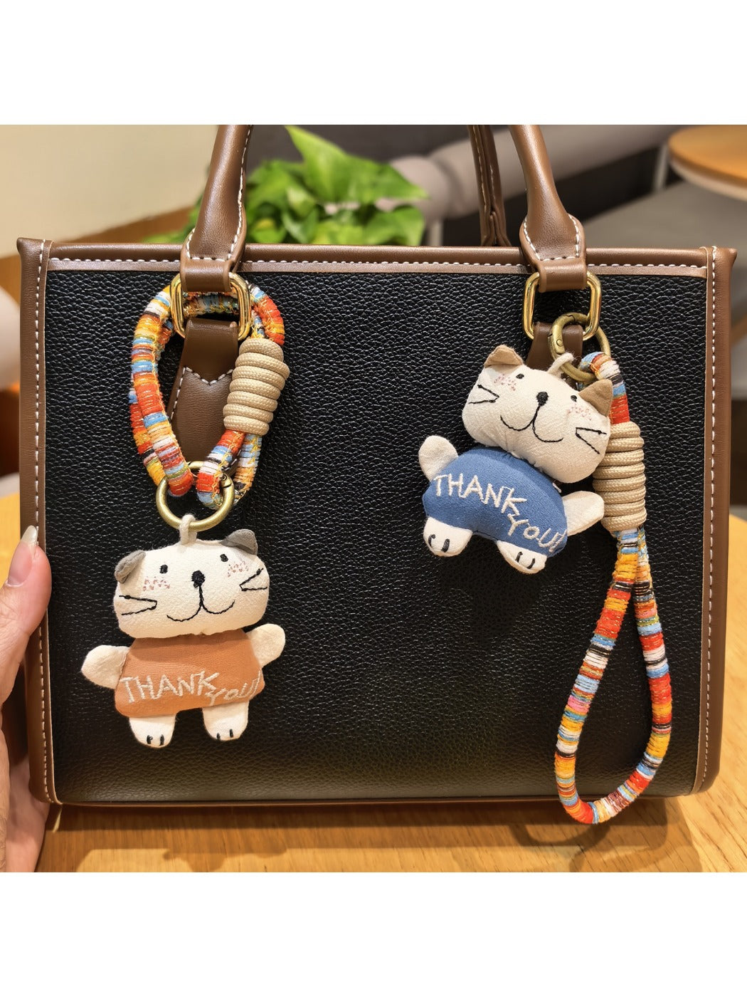 Trendy cat charm keychain hanging from a hand with blurred background