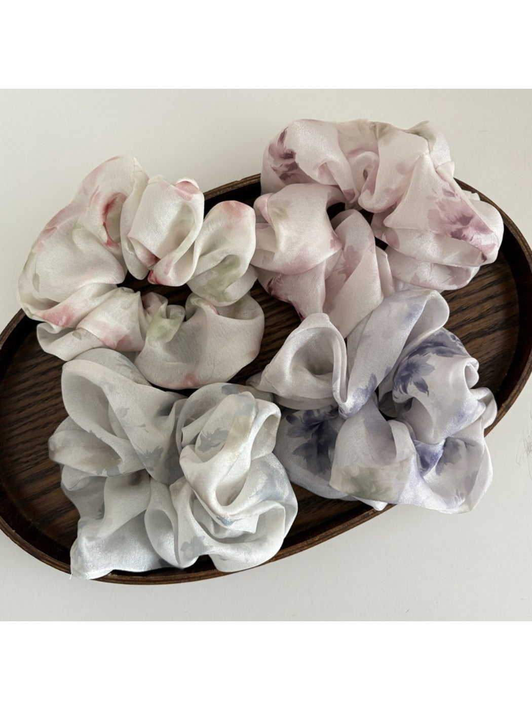 Close-up of Gifty satin hair scrunchie with colorful floral print on a white background