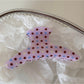 Beau pink hair clip with white polka dots displayed on a flat surface