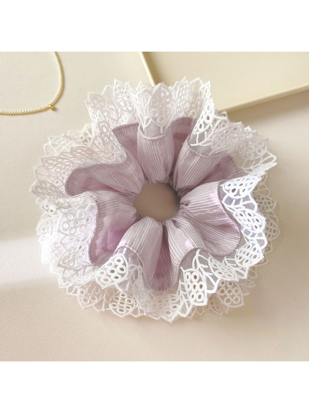 Close-up of Gifty purple scrunchie with delicate lace trim on a white background