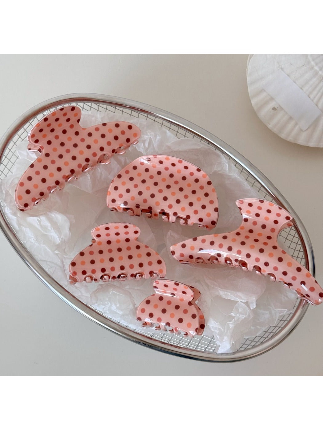 Close-up of Beau pink acetate hair clip with white polka dots on a white background