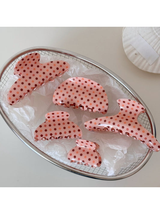 Close-up of Beau pink acetate hair clip with white polka dots on a white background