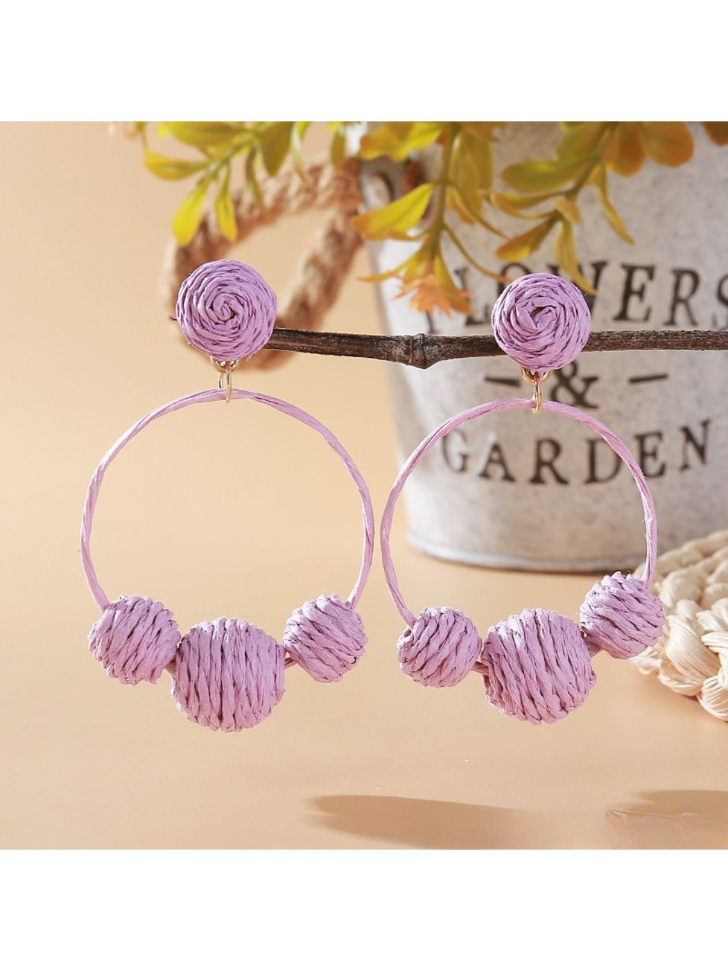 Earedge raffia round ball earrings with gold-tone hooks on a neutral background