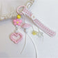 Pink mushroom keychain hanging from a set of keys on a wooden surface
