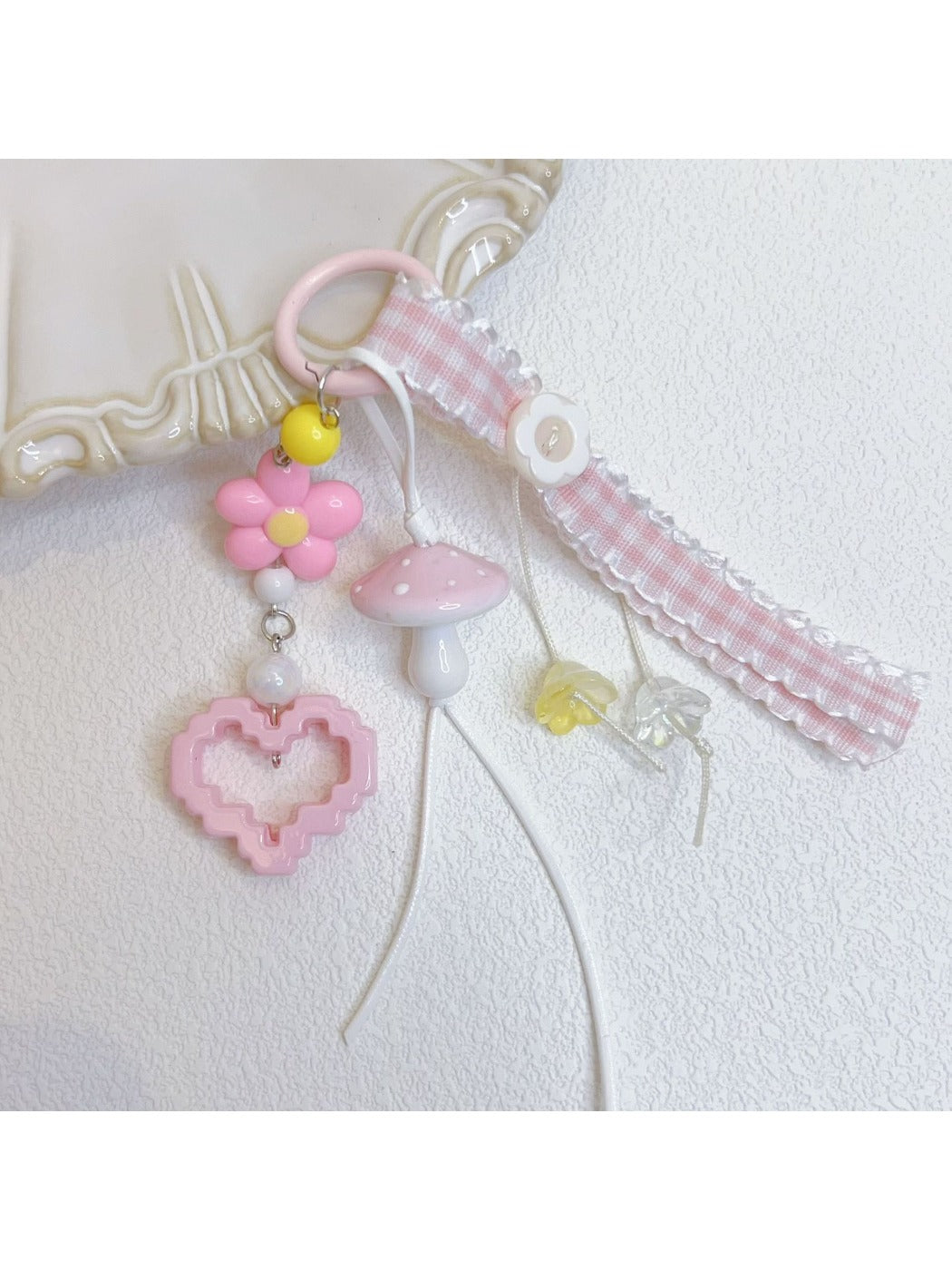 Pink mushroom keychain hanging from a set of keys on a wooden surface