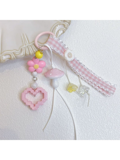 Pink mushroom keychain hanging from a set of keys on a wooden surface