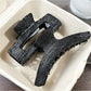 Close-up of Beau black acetate claw clip hinge and clasp mechanism