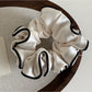 Pink satin scrunchie with ruffled design placed next to matching hairpins