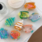 Close-up of Beau fish shaped claw clip showing vibrant blue and orange colors