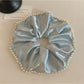 Gifty satin scrunchie with pearl beads styled in a woman's hair