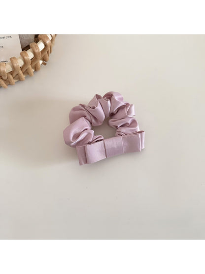 Model wearing the satin bow scrunchie styled with loose waves and a casual outfit