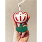 Pink tulip bag charm keychain next to a matching pink wallet
