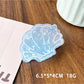 Beau claw clip placed on wooden surface showing glossy finish and ocean colors