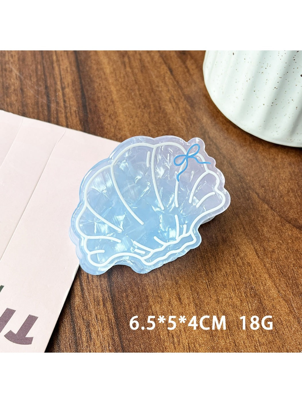 Beau claw clip placed on wooden surface showing glossy finish and ocean colors