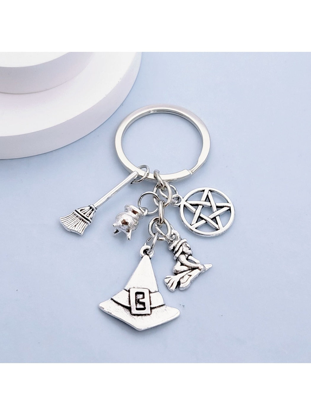 Alloy witch hat keychain with broom charm displayed on a white background