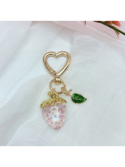 Keypus strawberry charm keychain next to a small notebook and pen