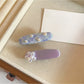 Beau hair clip featuring small purple flowers on a light background