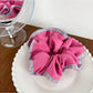 Side angle of magenta striped scrunchie showing fabric layers