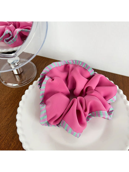 Side angle of magenta striped scrunchie showing fabric layers