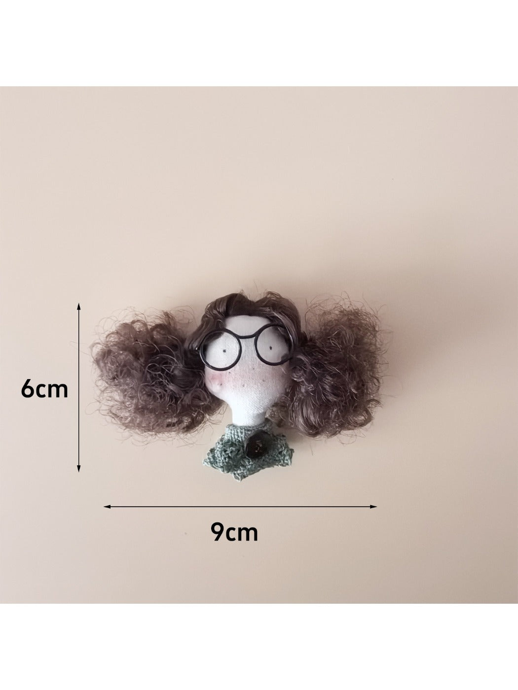 Fabric doll keychain hanging from a metal ring with curly hair and stitched dress