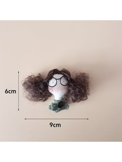 Fabric doll keychain hanging from a metal ring with curly hair and stitched dress