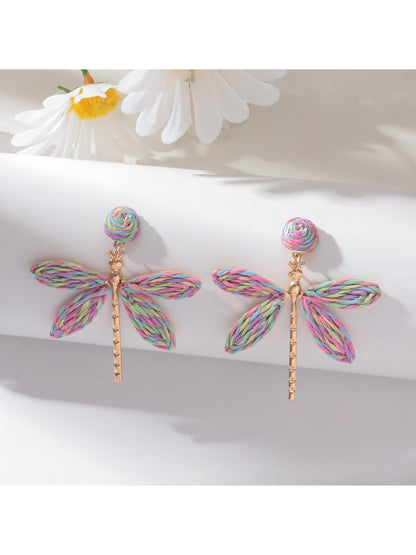 Raffia dragonfly earrings displayed with green leaves background