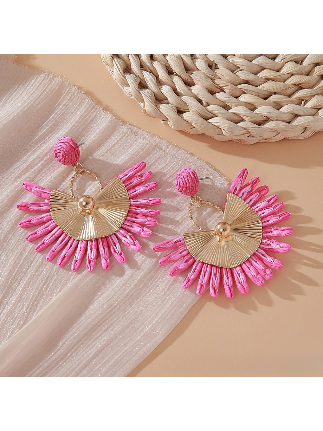 Side view of pink and black raffia woven earring showing texture and weave
