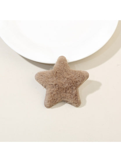 Plush star hair clip clipped onto a light pink fabric surface for display