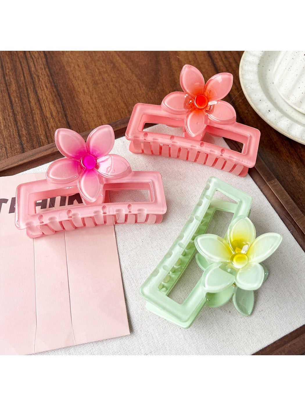 Beau square ombre flower shaped claw clip held in hand displaying size and color gradient