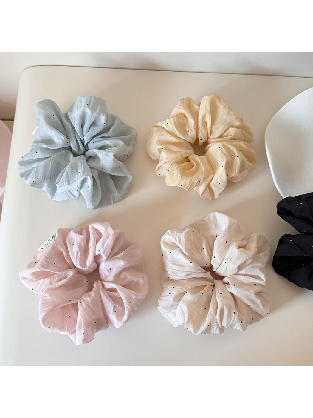 Close-up of Gifty soft polka dot scrunchie in pastel pink fabric with white dots
