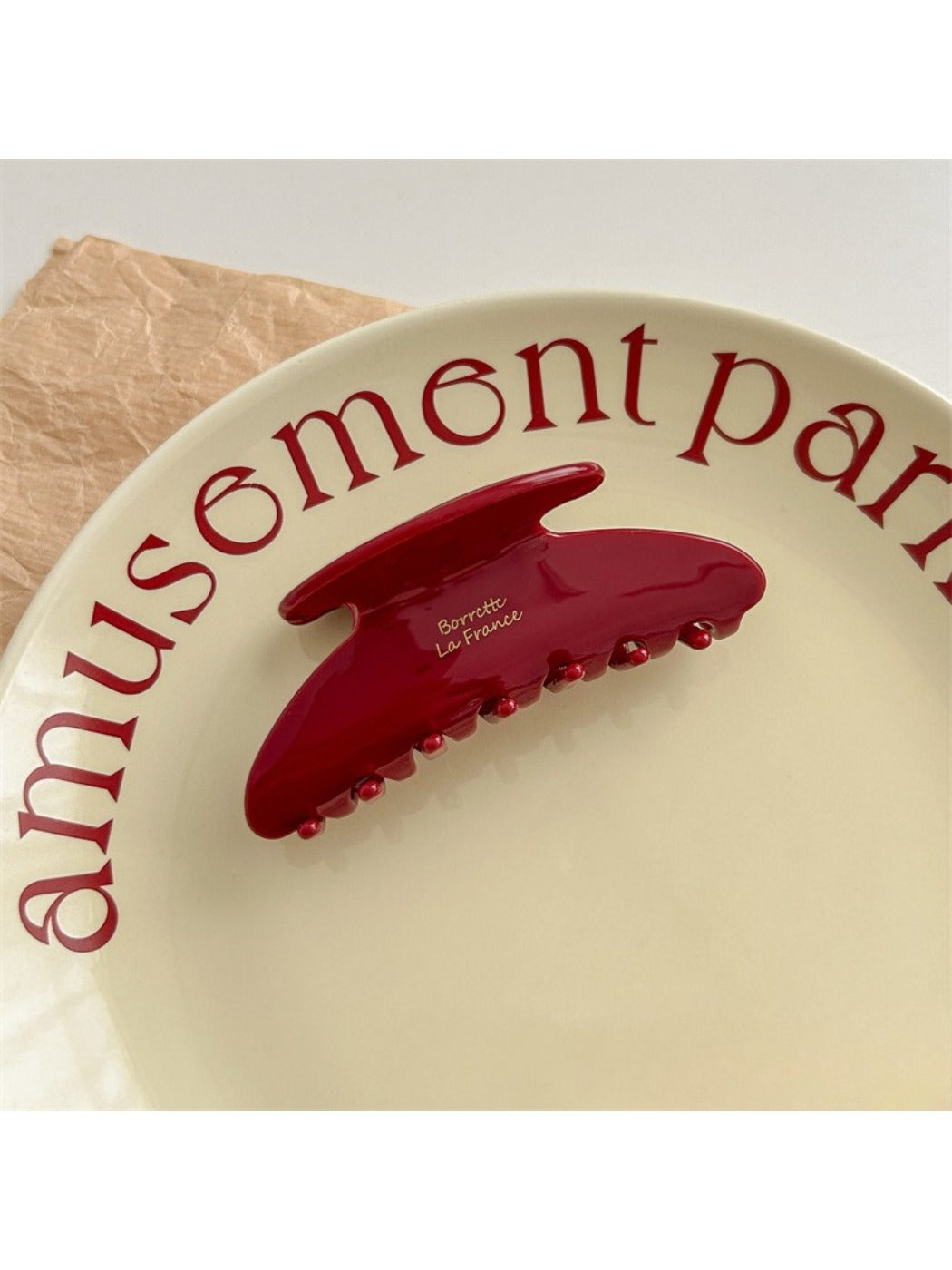 Beau red hair clip positioned on flat surface showing underside clasp mechanism