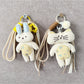 Close-up of fabric cat-shaped keychain with embroidered eyes and a metal keyring