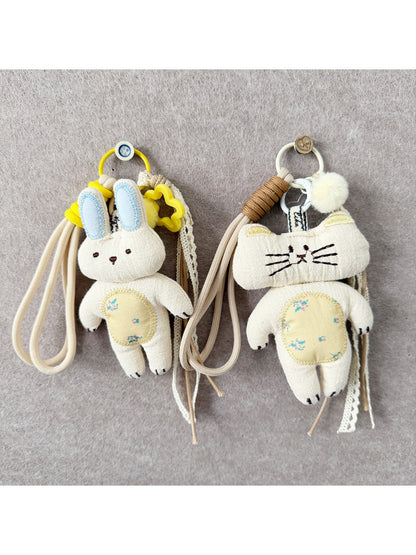 Close-up of fabric cat-shaped keychain with embroidered eyes and a metal keyring