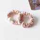 Strawberry hair tie worn on a model's wrist with a blurred background