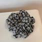 Multiple Gifty scrunchies stacked together showing consistent daisy pattern