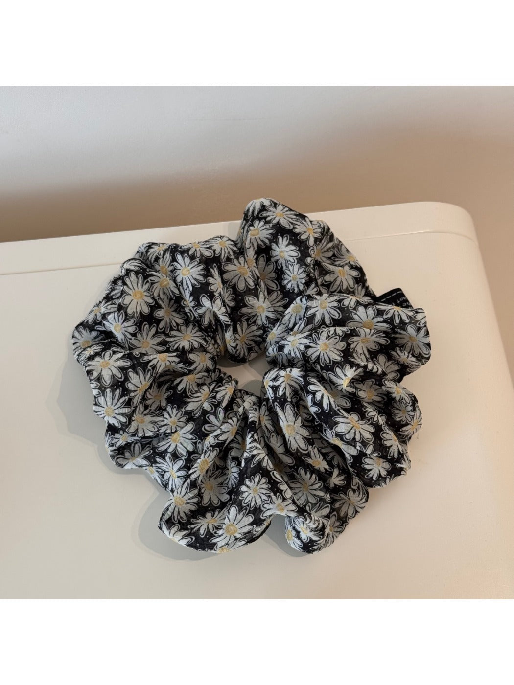 Multiple Gifty scrunchies stacked together showing consistent daisy pattern