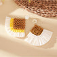Pair of vintage square raffia drop earrings displayed on a beige fabric surface