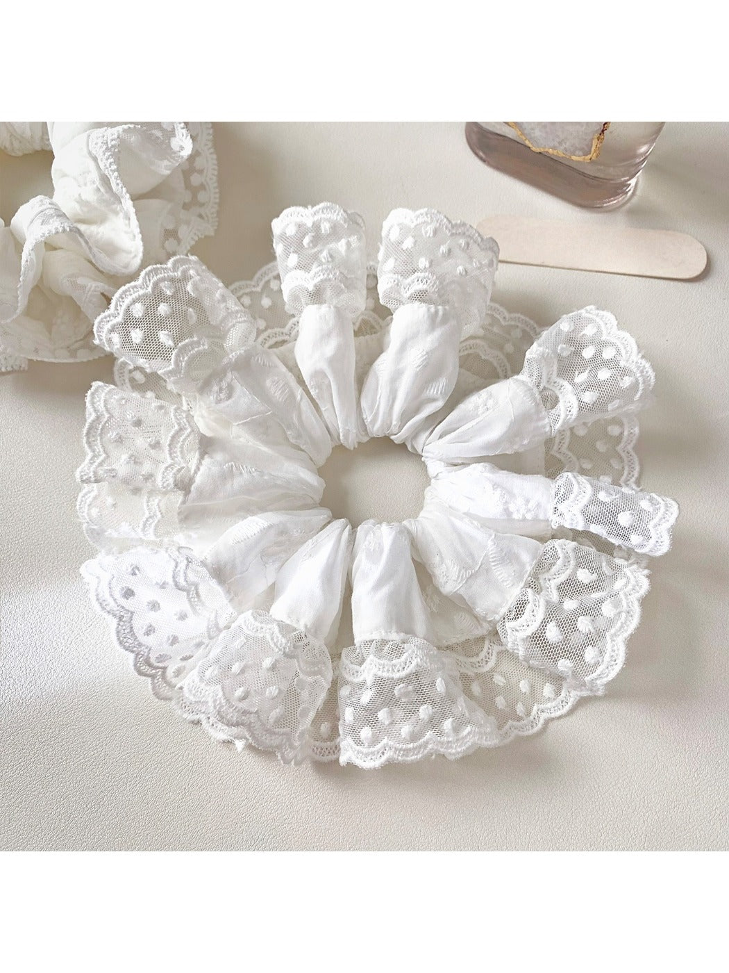 White lace trim scrunchie styled on a model's wrist