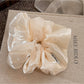 Beige satin scrunchie styled on a wrist as a bracelet accessory