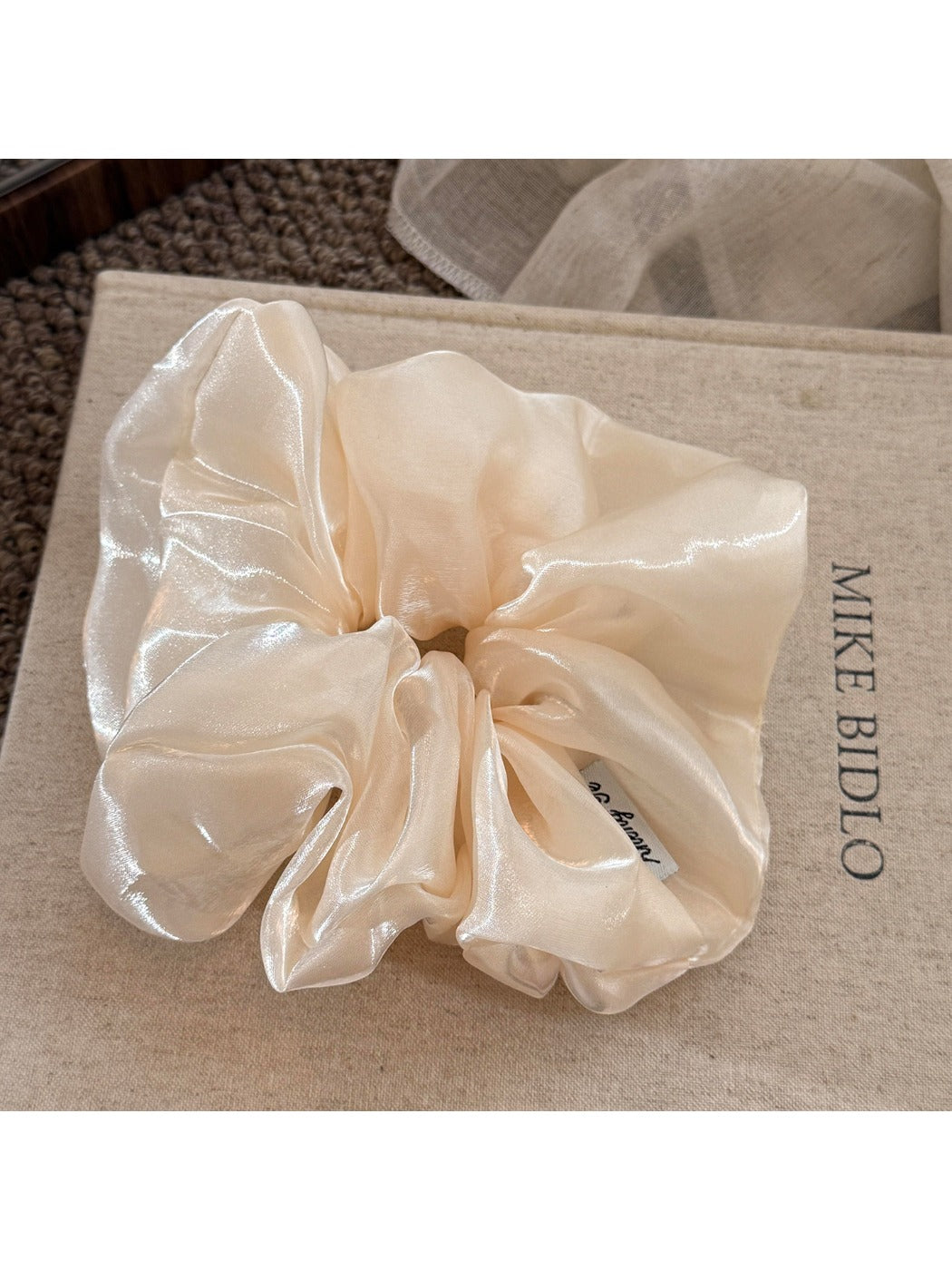 Beige satin scrunchie styled on a wrist as a bracelet accessory