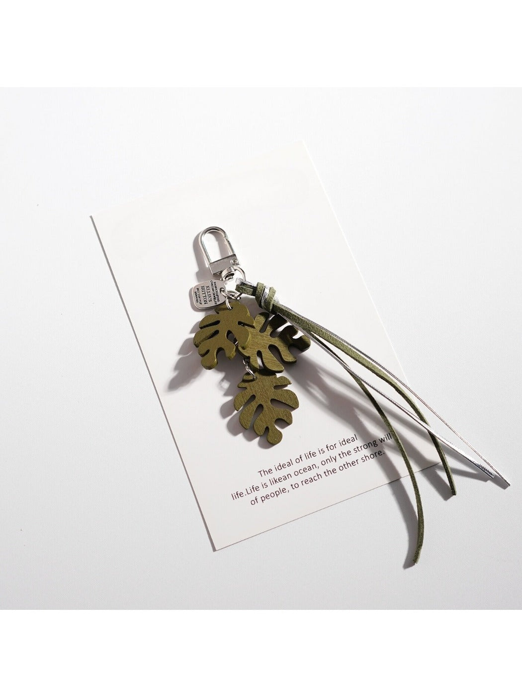 Keypus leaf shaped keychain attached to a set of keys on a wooden surface
