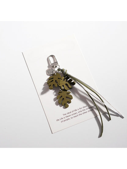 Keypus leaf shaped keychain attached to a set of keys on a wooden surface