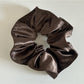 Model adjusting Gifty satin scrunchie in hair with natural outdoor lighting
