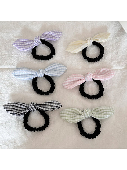 Close-up of Gifty plaid hair tie with a red bow embellishment on a white background
