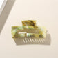 Beau hair clip placed on a wooden surface with natural light highlighting its pattern