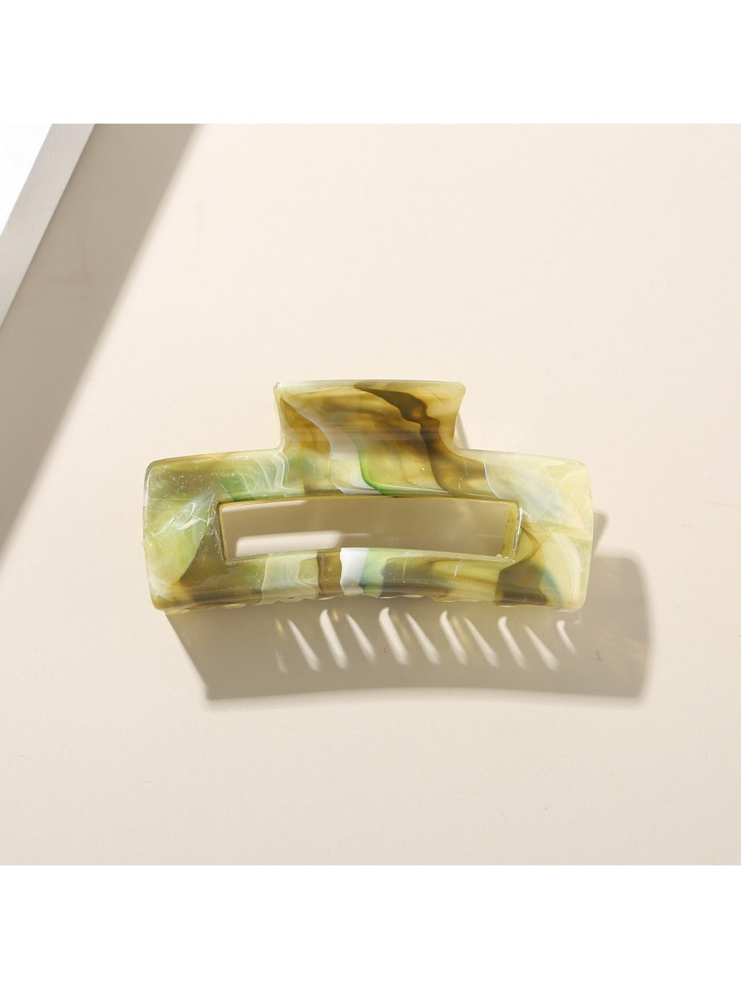 Beau hair clip placed on a wooden surface with natural light highlighting its pattern