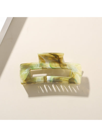 Beau hair clip placed on a wooden surface with natural light highlighting its pattern
