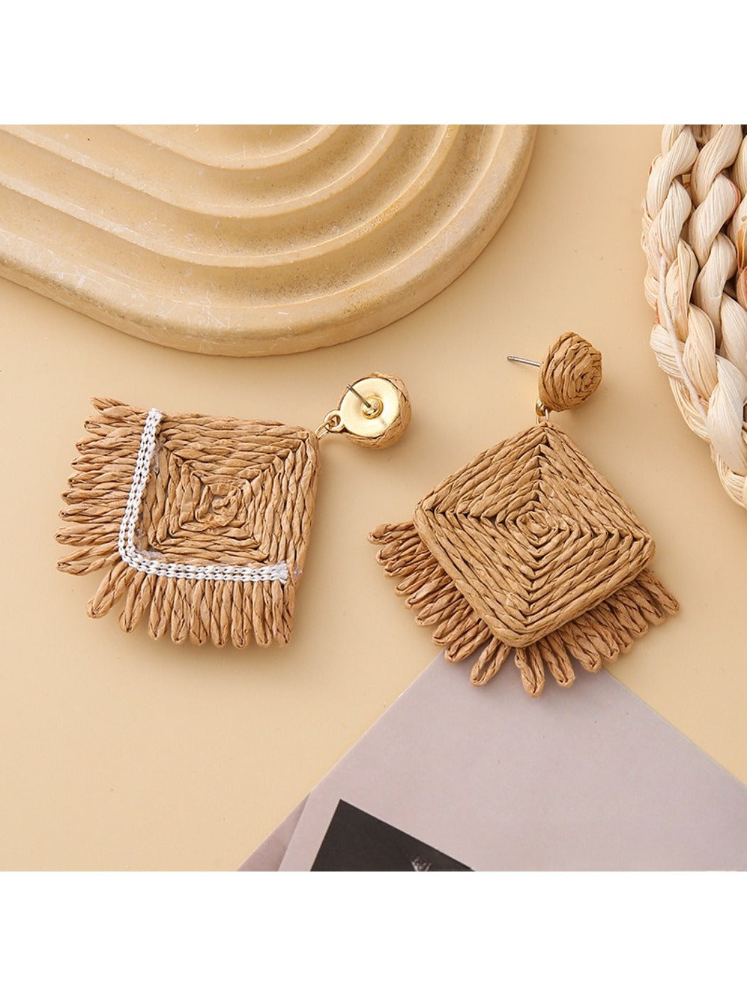 Earedge raffia square earrings displayed on a wooden surface