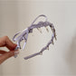 Pink fabric bow headband laid flat showing full design