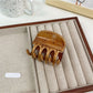 Beau hair claw clip placed on wooden surface with natural lighting